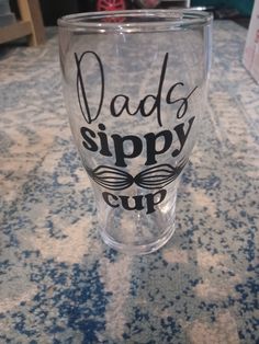 a glass that says dad's sippy cup sitting on a counter top with other items in the background