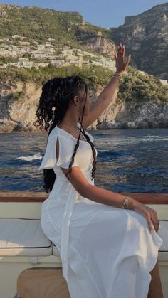 a woman sitting on the back of a boat waving