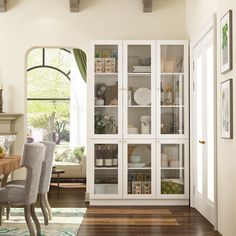 a white china cabinet with glass doors in a dining room