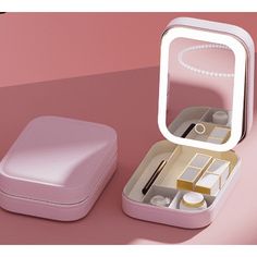 a small pink box with a mirror on the top and other items in it sitting next to each other