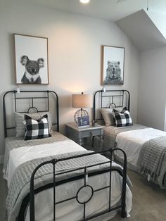 two beds in a room with pictures on the wall above them and one has a lamp