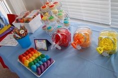 a table topped with lots of candy and cupcakes on top of blue cloth