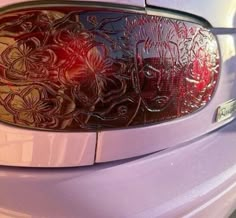 the rear end of a purple car with flowers etched on it's side window