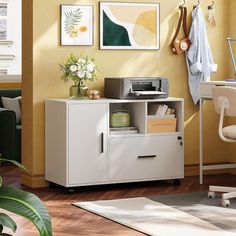 a white cabinet with drawers and a printer on it in front of a yellow wall