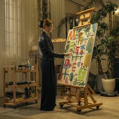 a woman standing in front of an easel painting