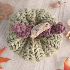 a crocheted pot holder with a wooden handle on top of leaves and acorns