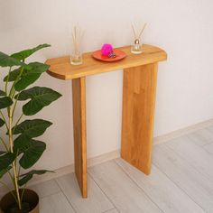 a wooden table with two candles on it next to a plant and potted plant