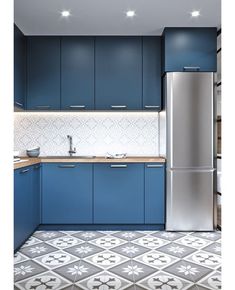 a kitchen with blue cabinets and tile flooring in the center, along with a stainless steel refrigerator freezer