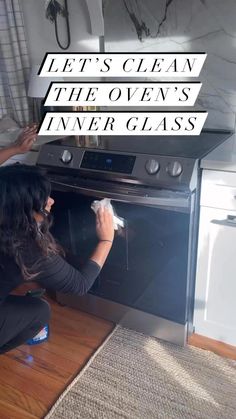 a woman is cleaning an oven with a rag and cloth on the floor next to it