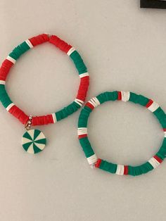 two bracelets with red, green and white beads sitting on top of a table