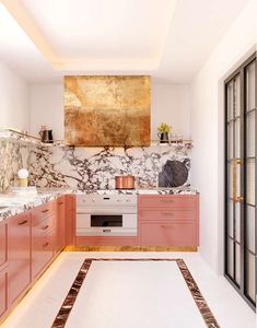 a kitchen with marble counter tops and pink cabinets, along with an area rug on the floor