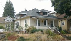 a yellow house with white trim on the front porch and stairs leading up to it