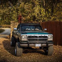 a pick up truck parked in front of a wooden fence with a sign on it