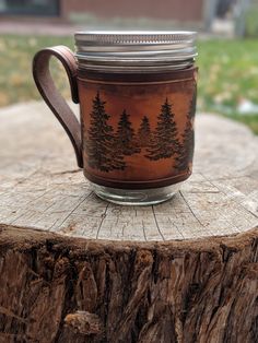 a mason jar sitting on top of a tree stump with trees painted on the inside