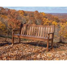 a wooden bench with a blanket on top of it in front of autumn leaves and trees