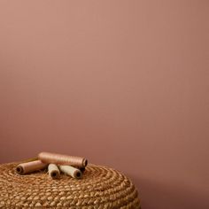 a basket with two rolled up cinnamons on top of it next to a pink wall