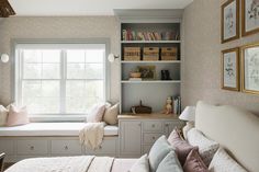 a bed sitting under a window next to a book shelf