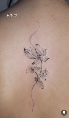 the back of a woman's shoulder with a flower tattoo on her left side