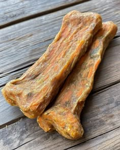 two raw dog treats are sitting on a wooden table, one is orange and the other is brown