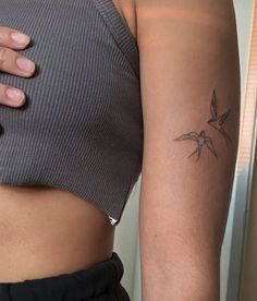 a woman's arm with a small bird tattoo on the left side of her body