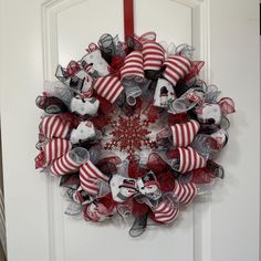 a red and white christmas wreath hanging on a door