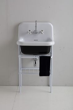 a white sink sitting on top of a metal shelf next to a black and white towel