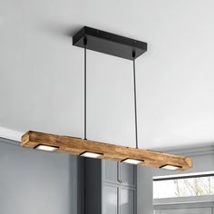 a wooden light fixture hanging from the ceiling in a kitchen with gray walls and cabinets