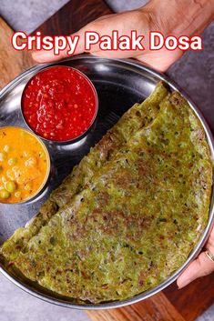 a person holding a plate with food on it that says crispy palak dosa