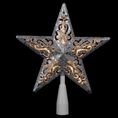 a silver and gold lighted star decoration on a white pole with an orange flame in the center