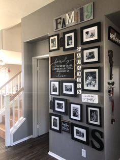 a wall with many framed pictures on it and some stairs leading up to the second floor