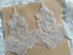 two pieces of white lace on top of a piece of brown paper with the words lacy and lily shop