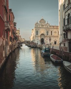 boats are parked along the side of a canal in an old city with tall buildings