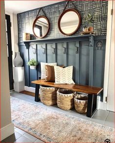 a bench with baskets and mirrors on it in front of a wallpapered entryway