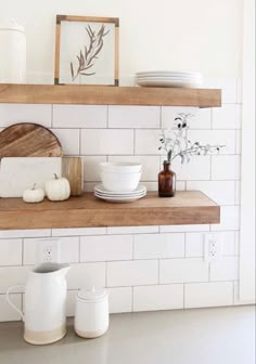 the shelves in the kitchen are filled with white dishes and vases on top of them