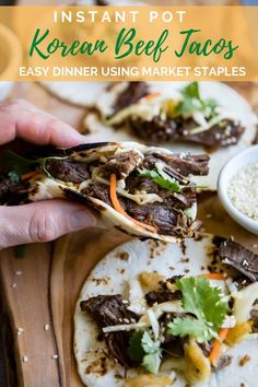 someone is holding up a beef tacos on a cutting board