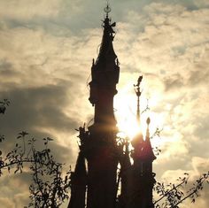 the sun shines through clouds behind a tall tower with clocks on it's sides