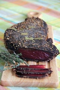 a wooden cutting board topped with sliced up beets on top of a colorful table cloth