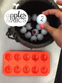 an orange plastic container filled with balls and numbers on top of a white countertop