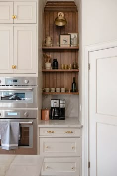 a kitchen with white cabinets and gold trimmings on the shelves above the stove