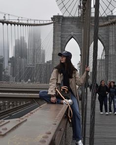 a woman sitting on the side of a bridge with her hand up in the air