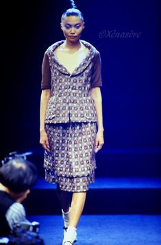 a woman walking down a runway wearing a dress