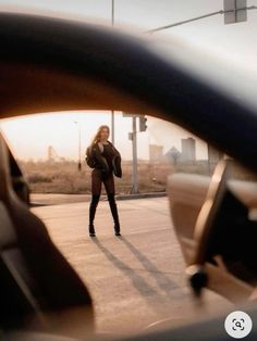 a woman walking across a street next to a car