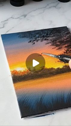 someone is painting a sunset scene with acrylic paint