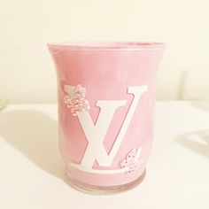 a pink vase with white letters and flowers on the bottom is sitting on a table