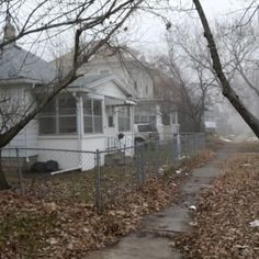 a white house sitting on the side of a road next to a leaf covered sidewalk