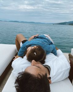 a man laying on the back of a boat while holding a child