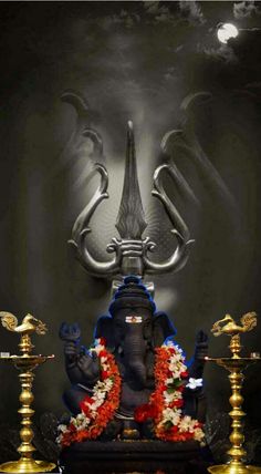 an elephant statue sitting on top of a table next to two candles and a lamp