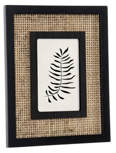 a black and white frame with a fern leaf on the front, against a burlock background