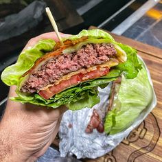 a hand holding a sandwich with meat and lettuce