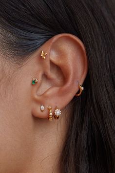 a close up of a woman's ear with three different piercings on it